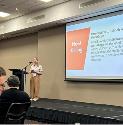 Neve from Blind Low Vision NZ giving a presentation at a conference.