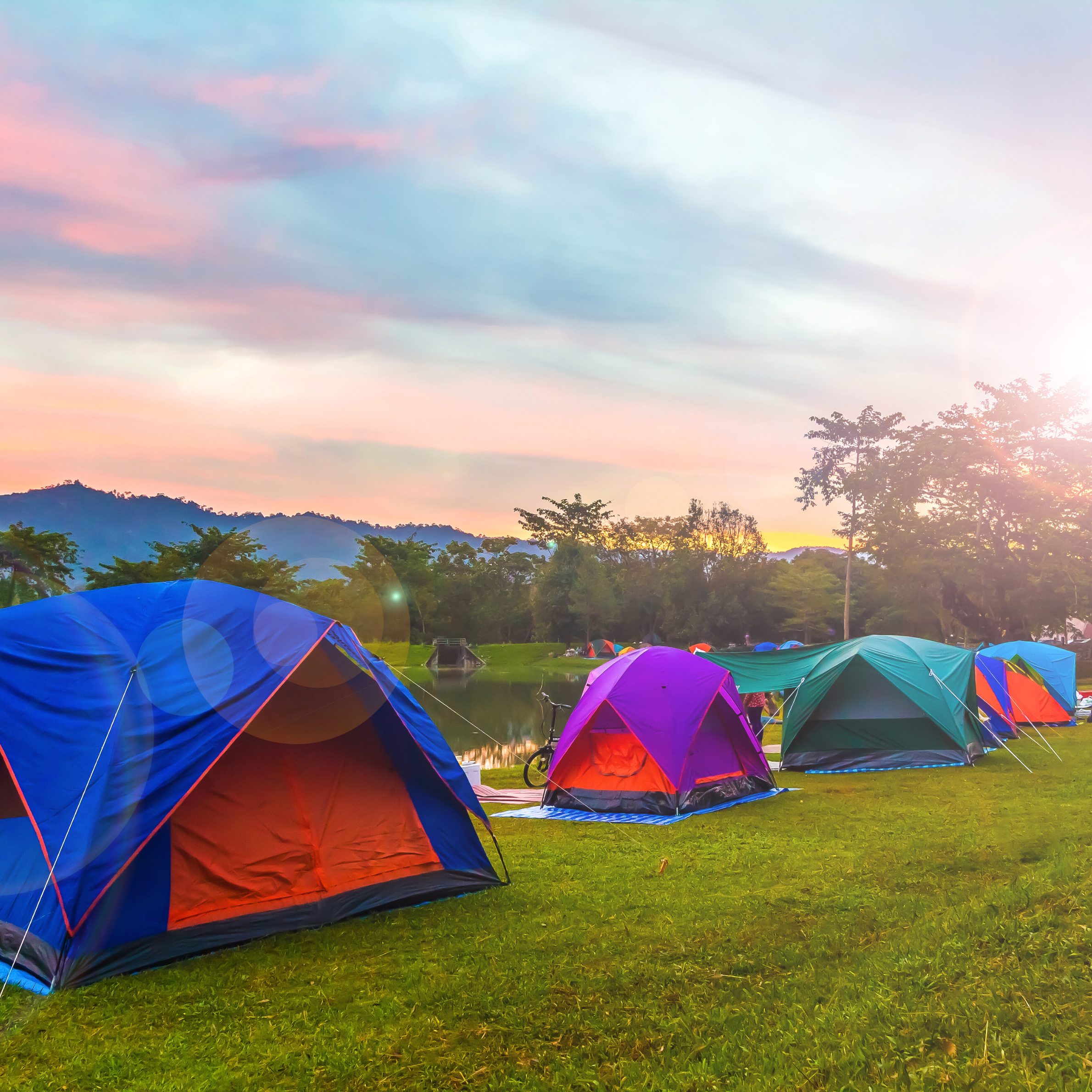 Green campground with several colourful tents.