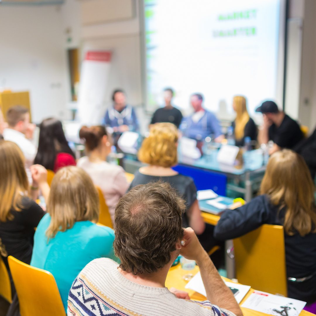 A group of people sitting at tables in a conference room.