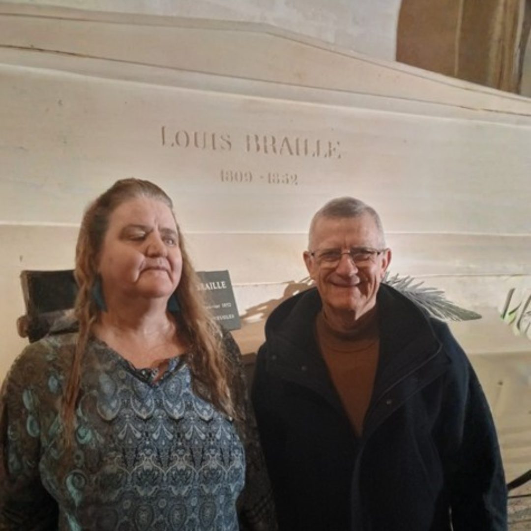 A man and woman standing in front of a sign that says Louis Braille.