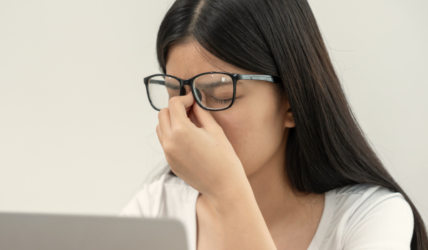 A woman rubs her eyes and looks tired.