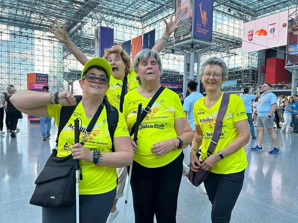 Four women in bright Achilles NZ jerseys posing for the camera. 